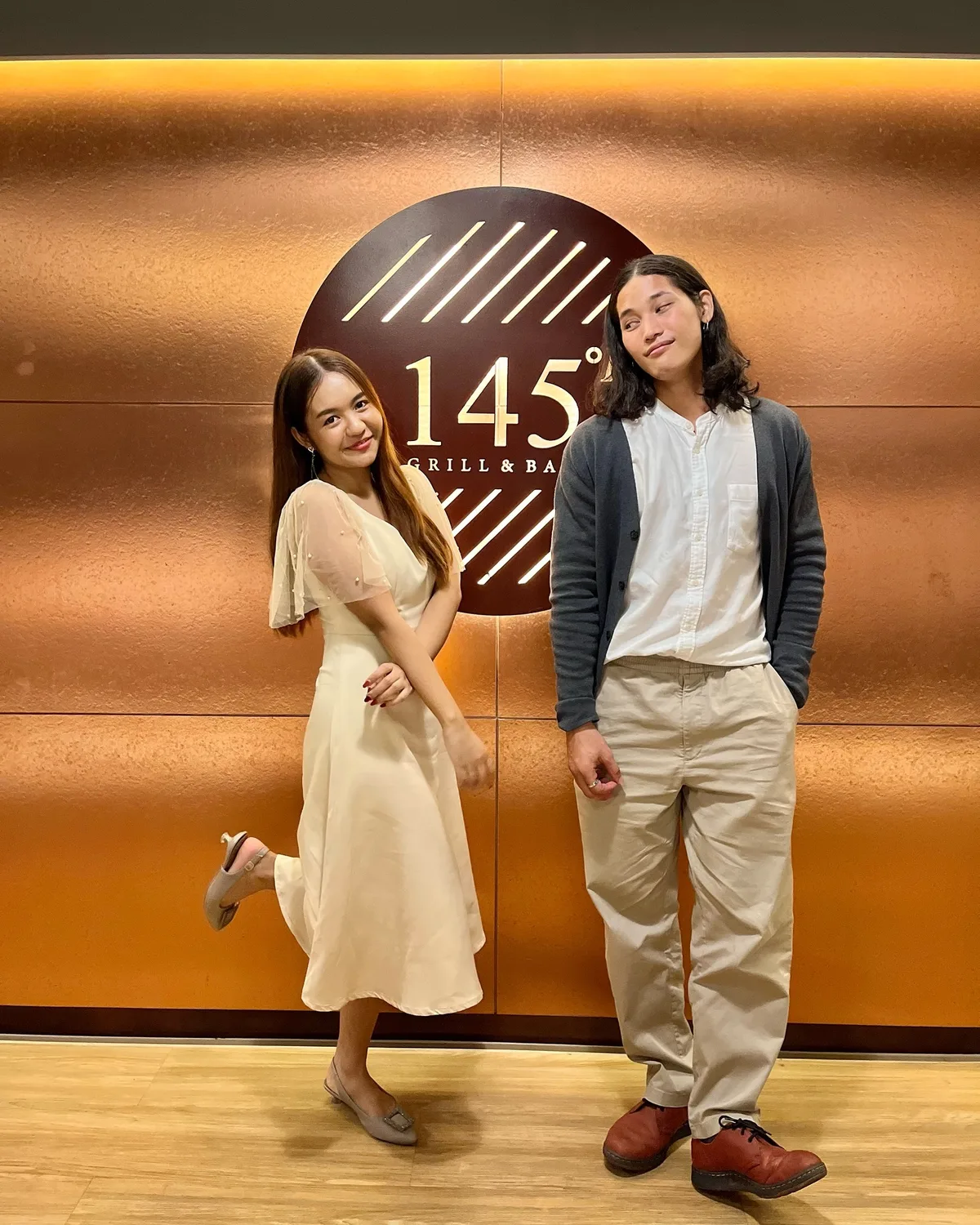 คู่แขกถ่ายภาพหน้าผนังโลโก้ 145°F Grill & Bar